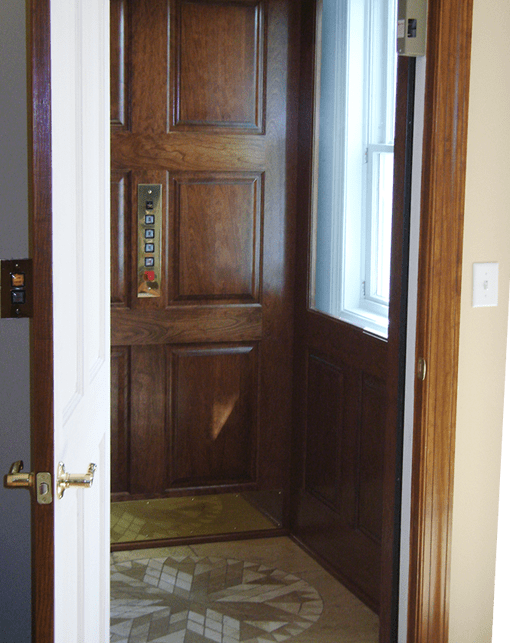 open hinged door to wood panellled and brass inlayed elevator