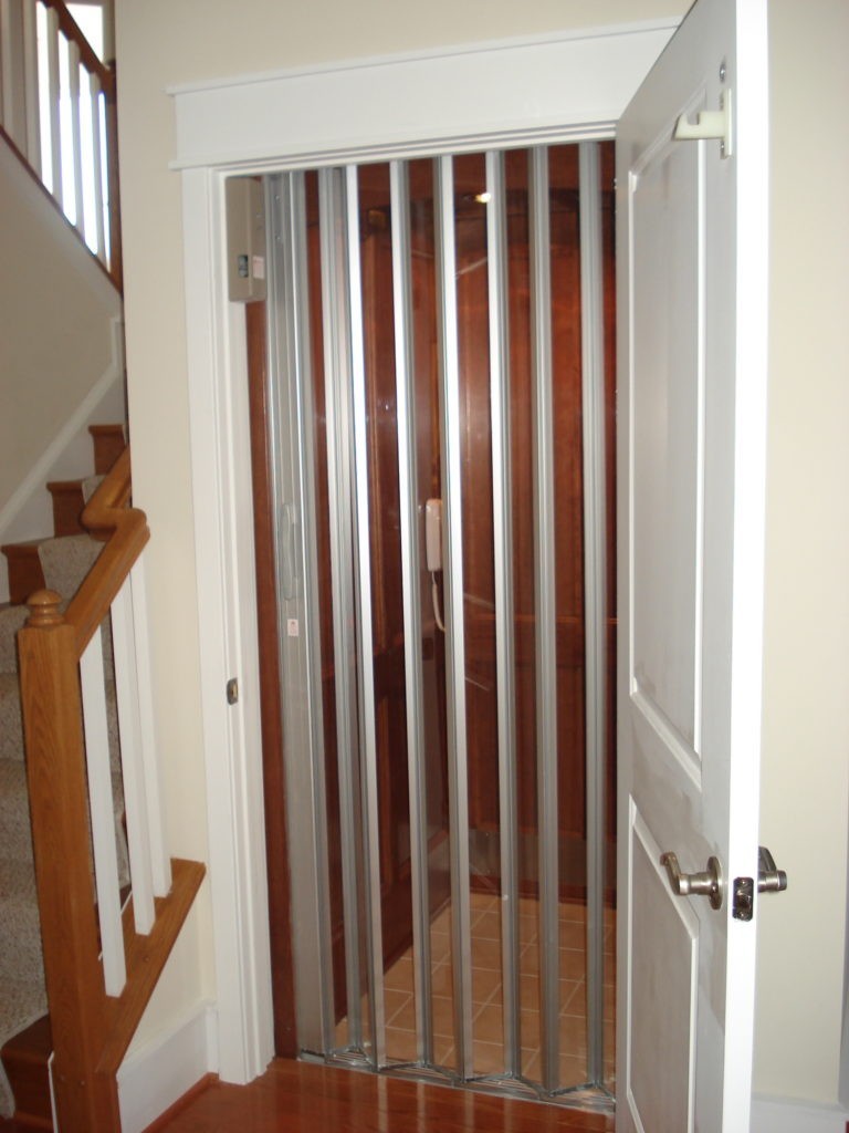 open hinged door to closed glass panel accordian style door to residential elevator